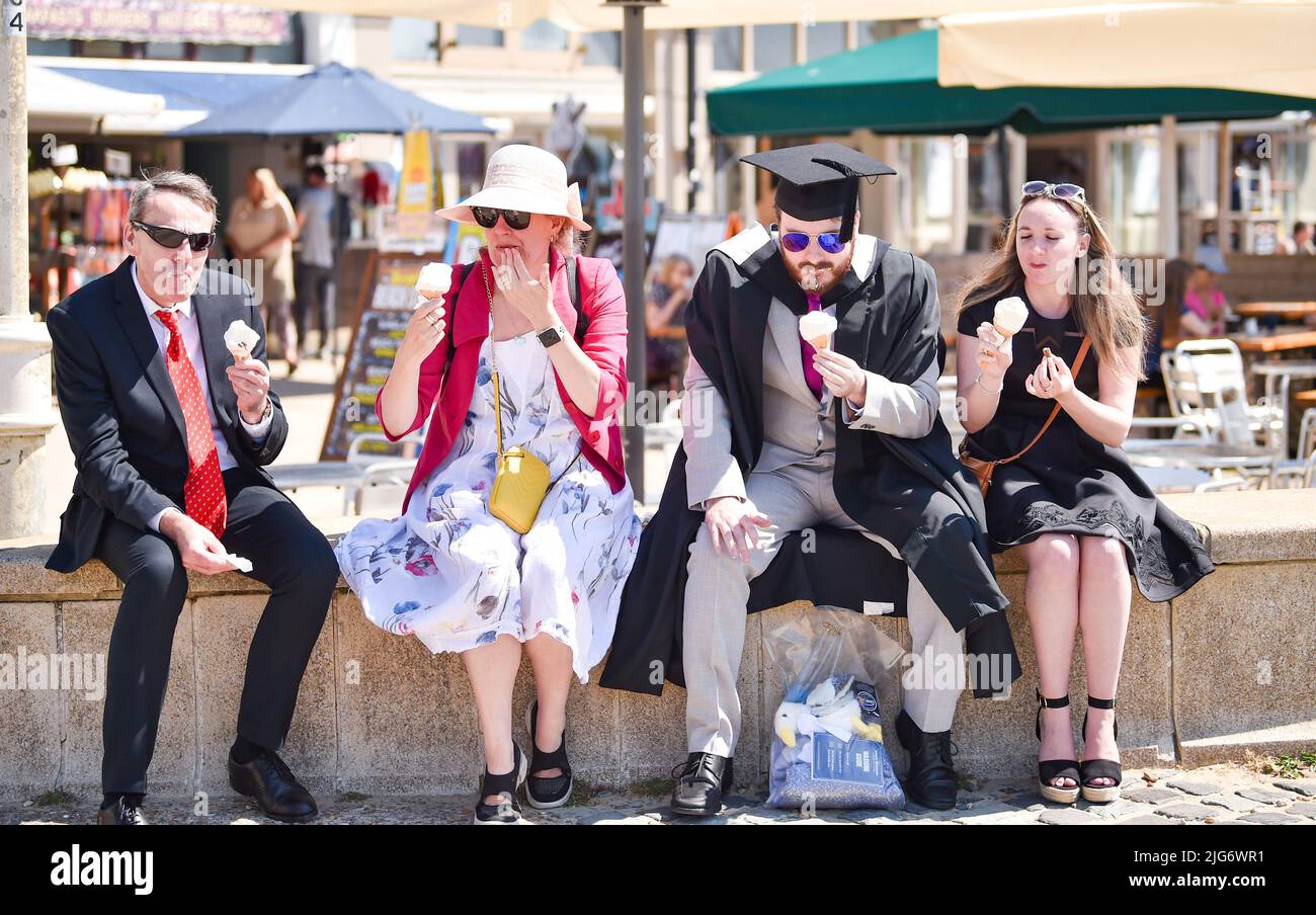 Brighton, Großbritannien. 8.. Juli 2022. Ein Student und eine Familie der University of Sussex genießen ein Eis an der Küste von Brighton bei schönem, heißem Sonnenschein nach der Abschlussfeier. Für Teile Großbritanniens wird für die nächste Woche eine mögliche Hitzewelle prognostiziert. : Credit Simon Dack/Alamy Live News Stockfoto