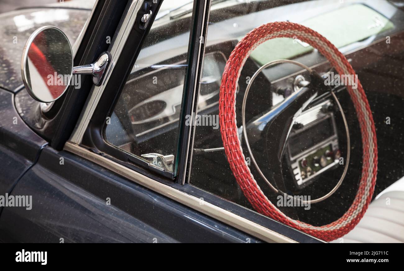 Rotes Lenkrad und Rückspiegel eines alten Zeitfahrzeugs. Nahaufnahme mit weichem selektivem Fokus Stockfoto