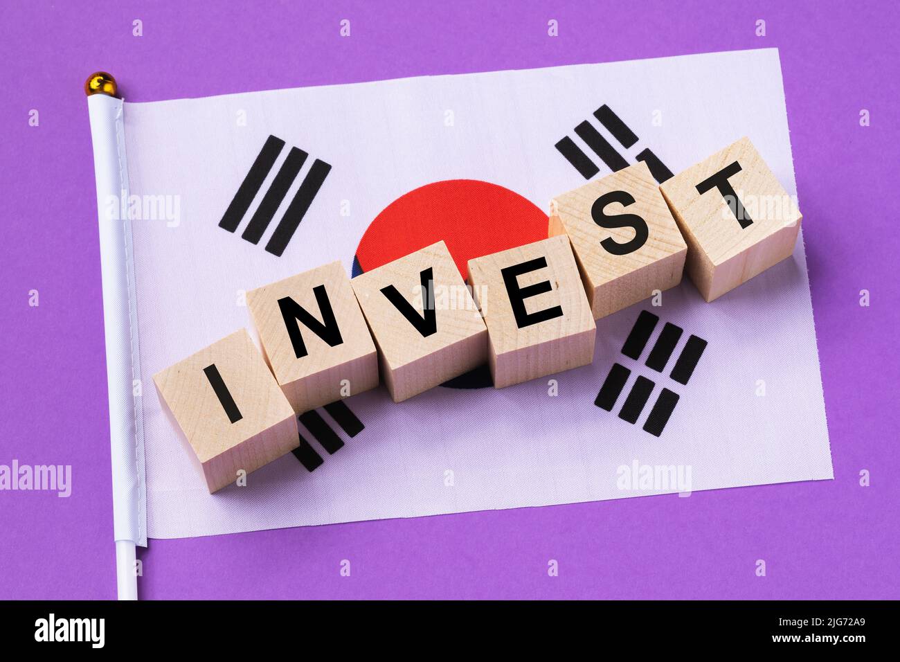 Holzwürfel mit Text und einer Flagge auf farbigem Hintergrund, das Konzept der Investition aus Südkorea Stockfoto