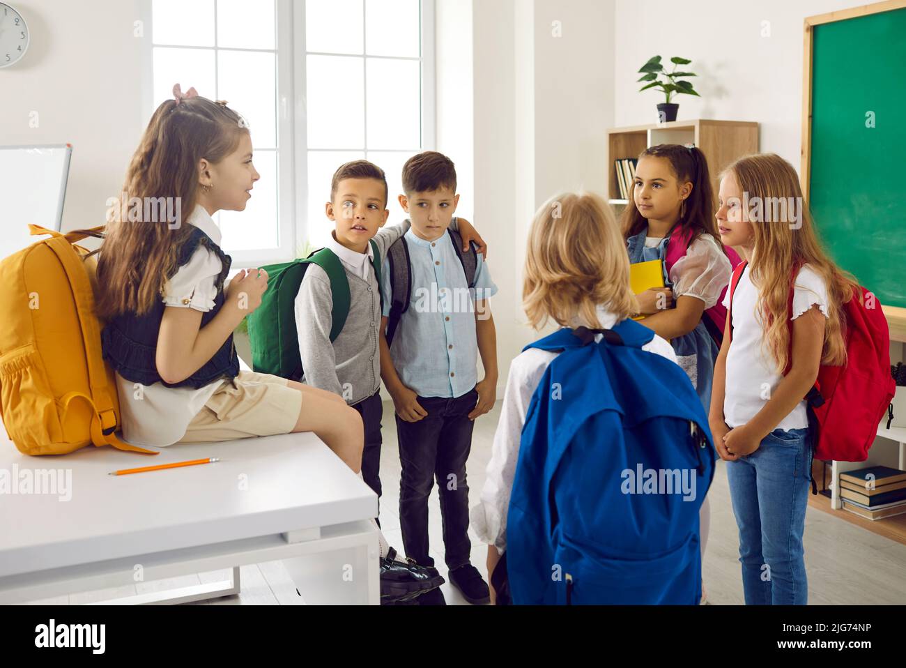 Kleine Schulkinder haben Spaß im Klassenzimmer während des Wiedersehens nach langen Schulferien zu reden. Stockfoto