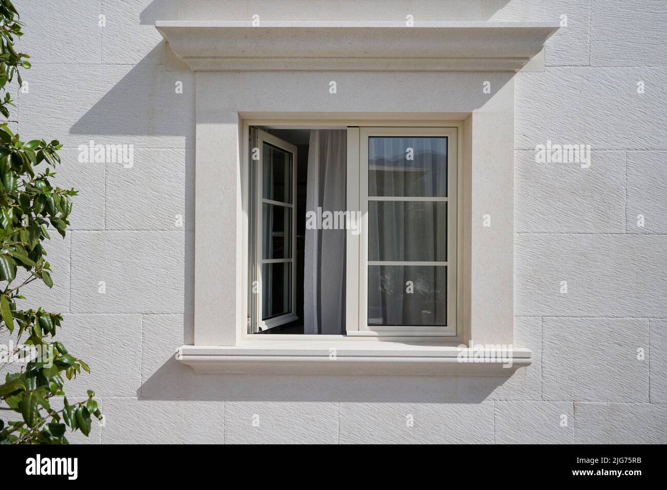 Beigefarbene Wand mit offenem, eleganten PVC-Fenster. Stockfoto