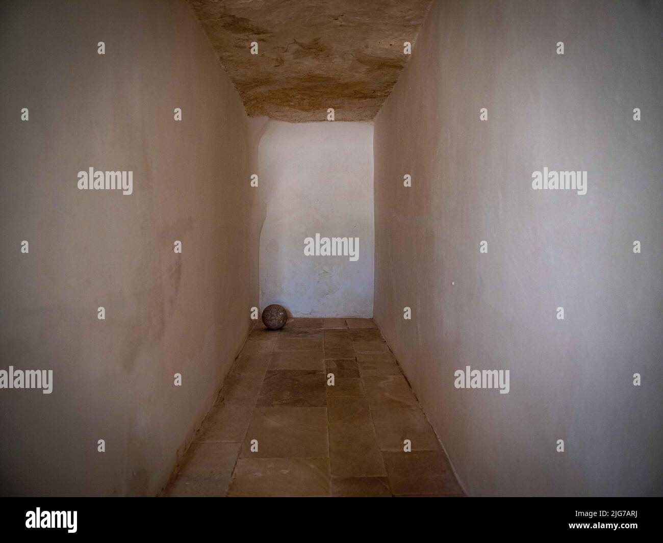 Abstrakte Platzierung einer Kanonenkugel am Ende eines langen leeren Korridors in der Burg von Otranto, Apulien, Italien Stockfoto