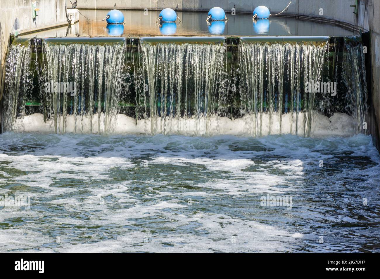 Blaue Bojen schweben über dem fallenden Wasser an der San Antonio River Lock and Dam in Texas. Stockfoto