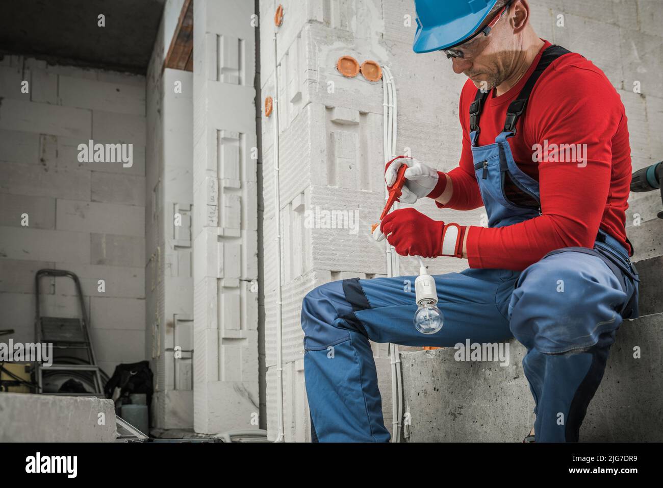 Professioneller Auftragnehmer Elektriker Vorbereitung Lichtpunkt In Neu Entwickelten Beton Bricks House. Kaukasischer Arbeiter in seinem 40s. Stockfoto