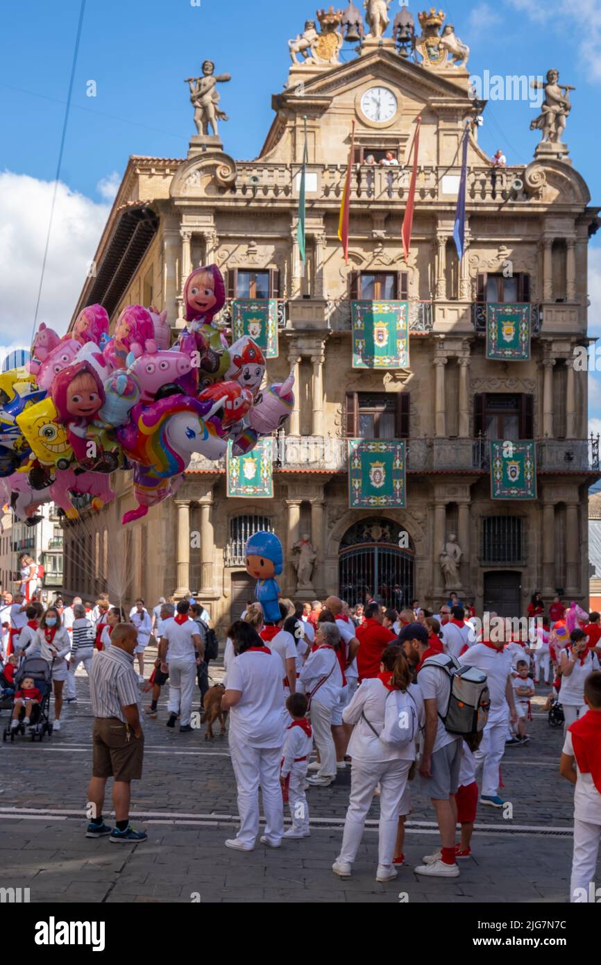 Die Menschen auf der Straße genießen die Atmosphäre des San Fermin-Festes in traditioneller weißer und roter Kleidung mit roter Krawatte auf dem Rathausplatz Stockfoto