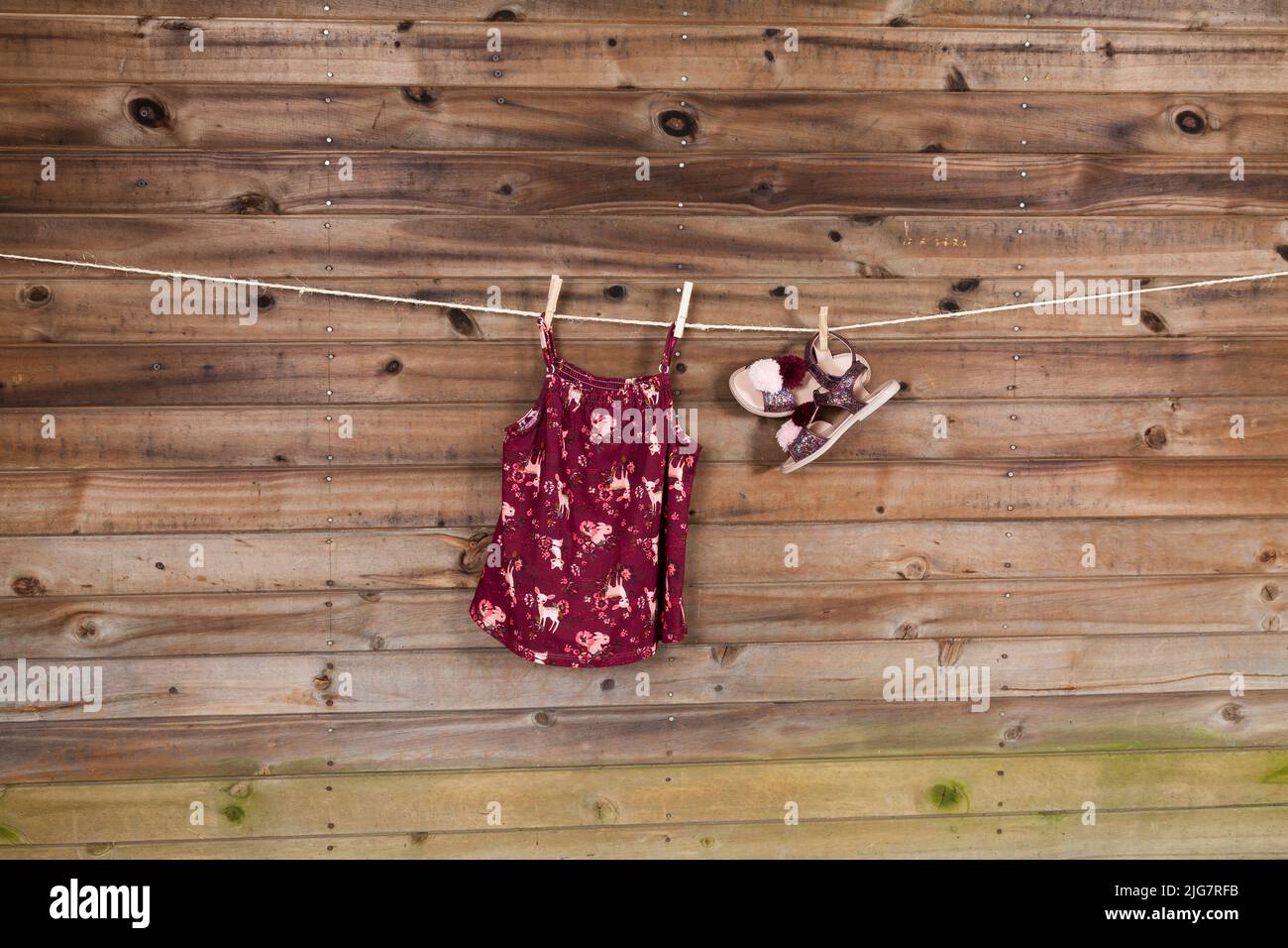 Kindermode Set aus Mädchenbekleidung, Kleid mit Sandalen; Foto auf Holzhintergrund. Stockfoto
