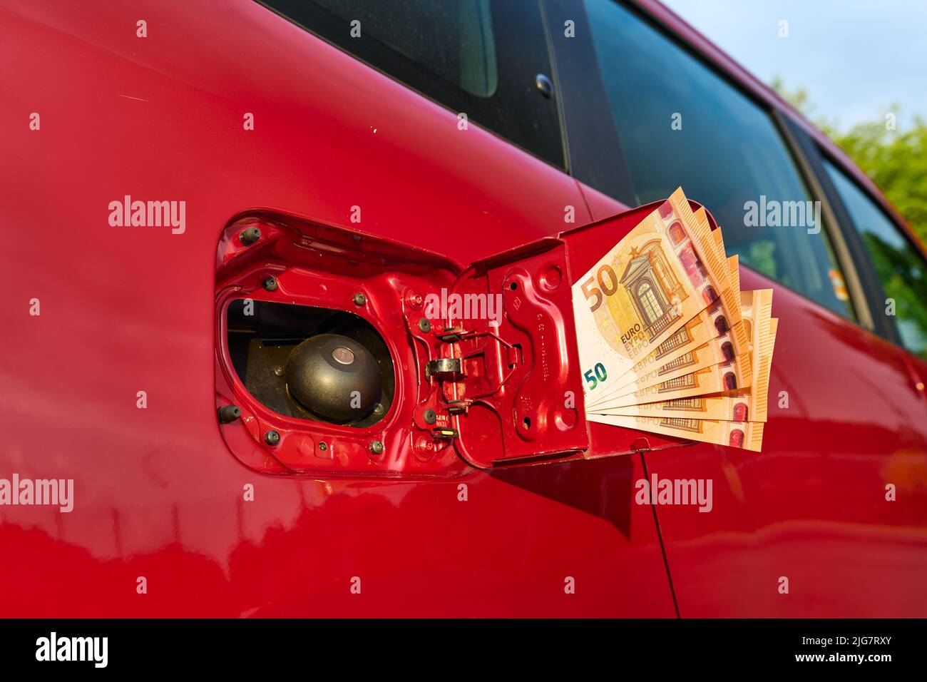 Nahaufnahme von vielen 50-Euro-Rechnungen am Kraftstofftank eines Autos, steigende Kraftstoffpreise, die an der Tankstelle bezahlen. Stockfoto