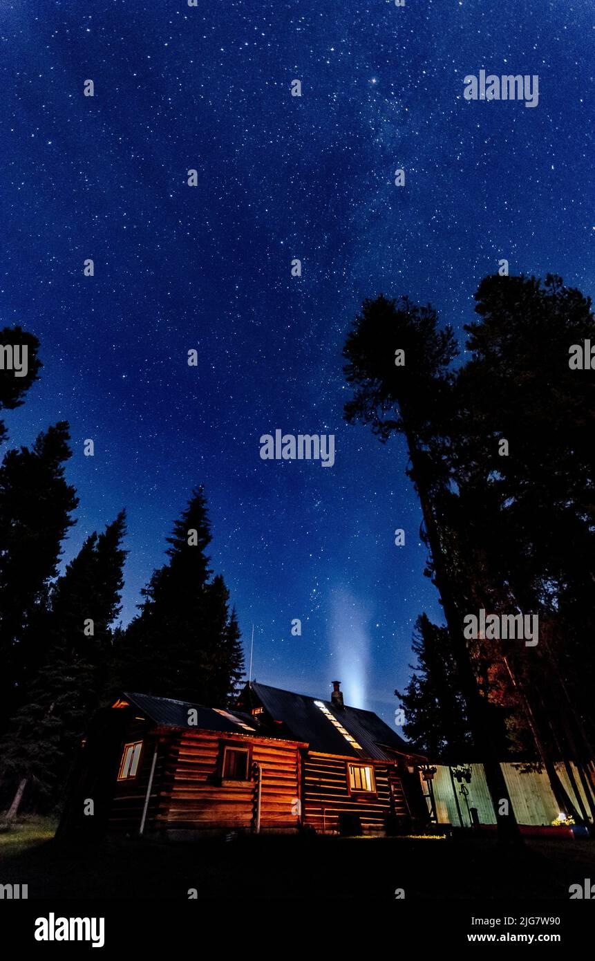 Eine Aufnahme einer Holzhütte im Flathead National Forest in der Nähe des Glacier National Park vor Sternenhimmel Stockfoto