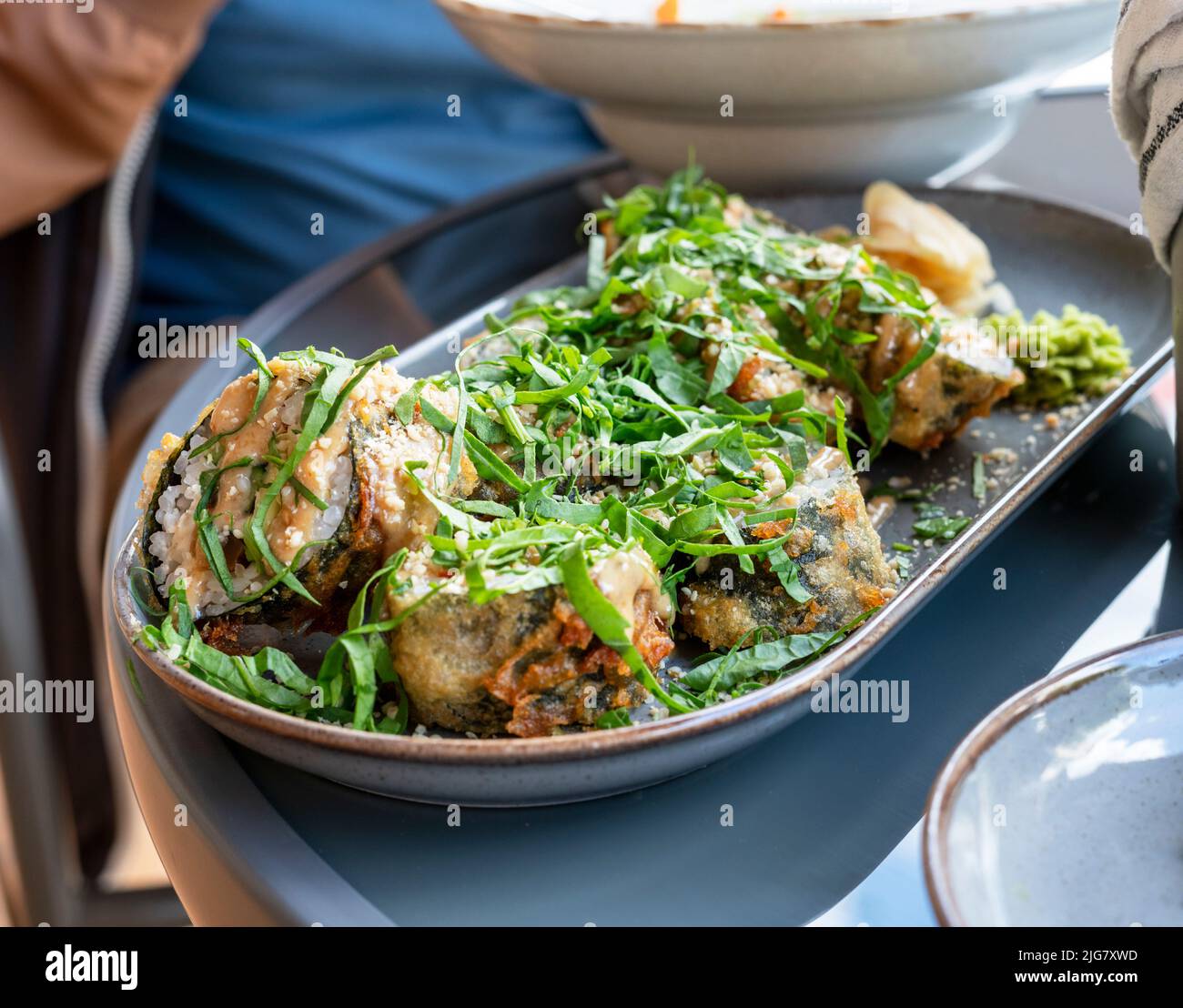 Tempura vegane Sushi-Rollen mit Auberginen und Grünpflanzen in einem Café gesunde vegetarische Küche Asiatische Küche selektiver Fokus Stockfoto