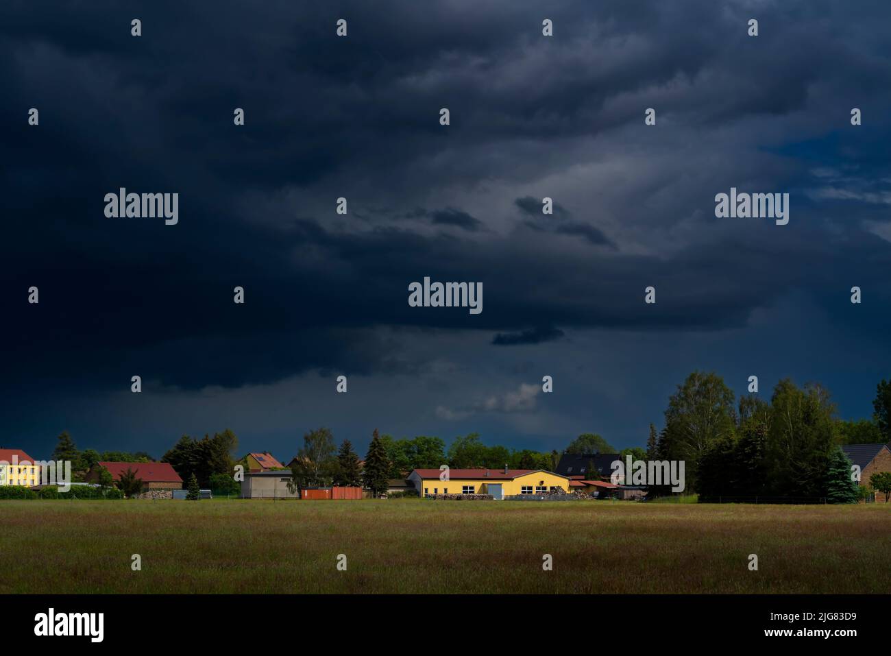 Extreme Regenwolken kurz vor einem starken Sturm im Frühjahr über einem kleinen Dorf in Deutschland im Land Brandenburg Stockfoto