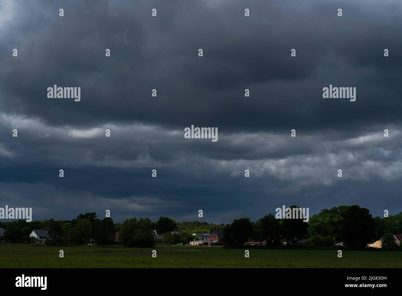 Extreme Regenwolken kurz vor einem starken Sturm im Frühjahr über einem kleinen Dorf in Deutschland im Land Brandenburg Stockfoto