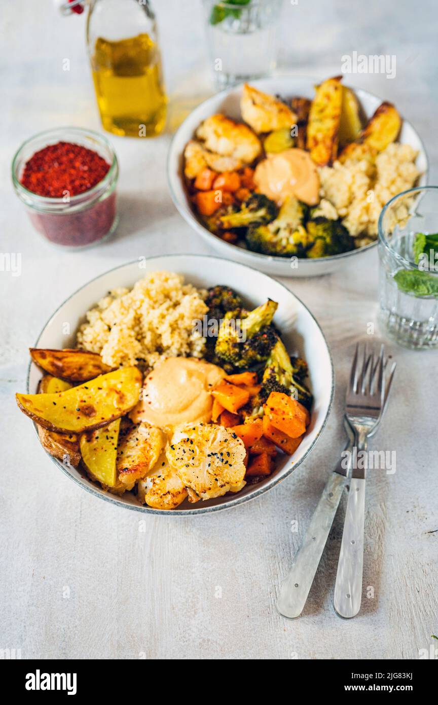 Geröstete Kartoffeln, Süßkartoffeln, Brokkoli mit braunem Reis und Hummus-Dressing, vegan Stockfoto