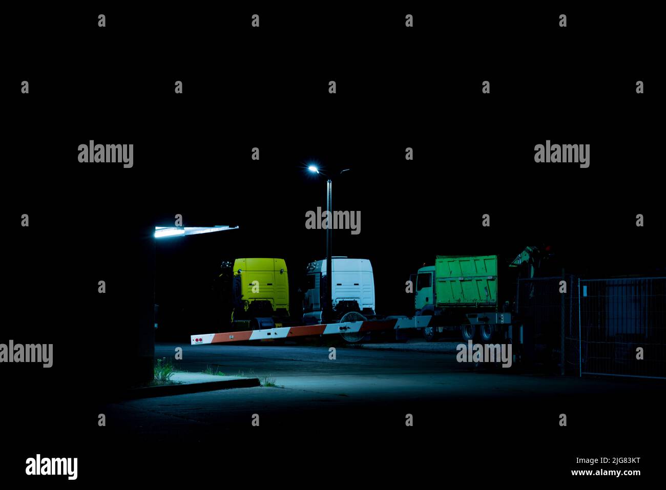 Geparkte Lastwagen nachts unter einem Flutlicht auf einem Industriegelände Stockfoto