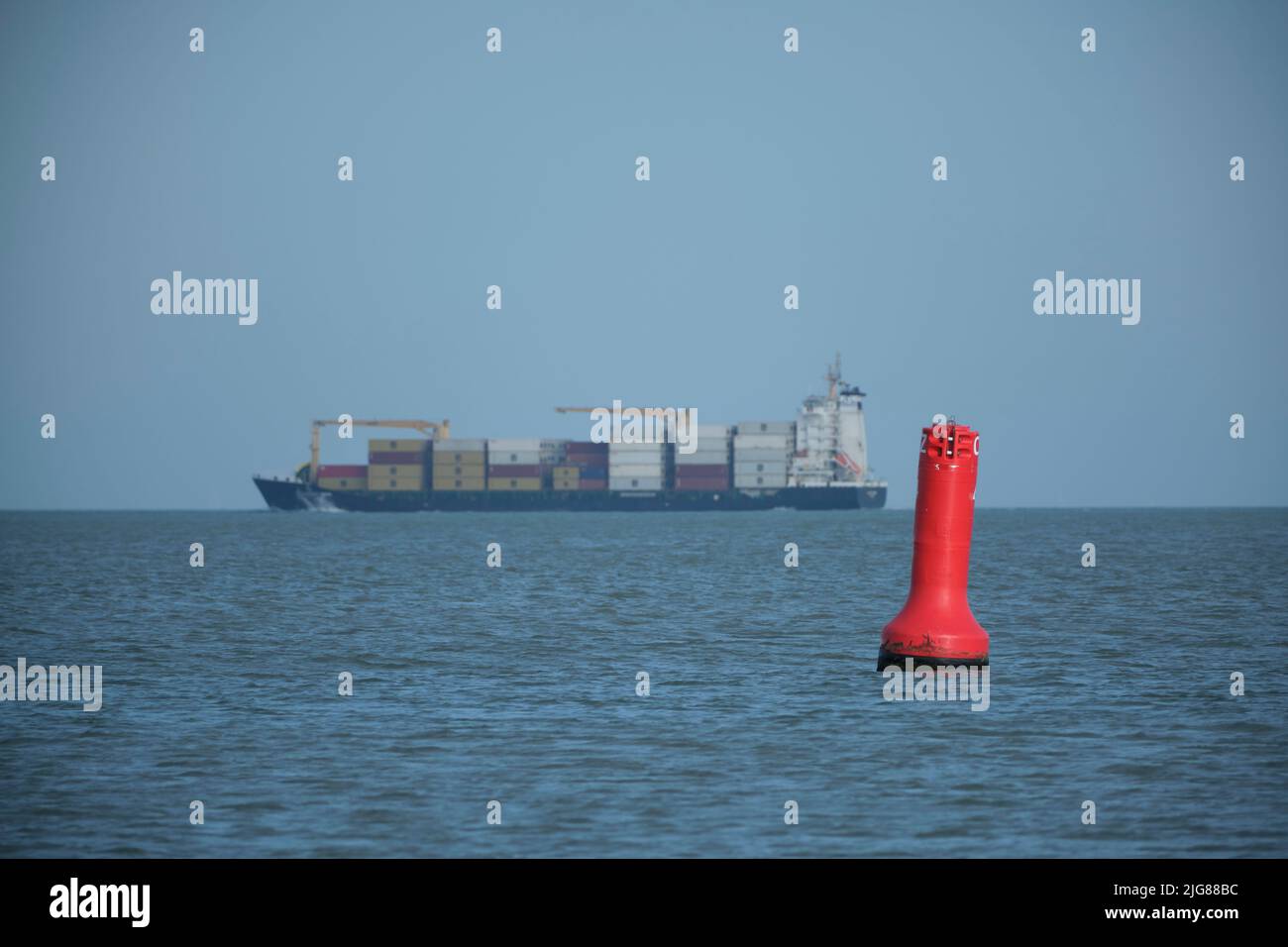 Eine schwimmende Boje aus rot-weißem Stahl und ein lrge Containerschiff im blauen Meerwasser treiben mit der Meereswelle zwischen den weiten Ozeanen Stockfoto