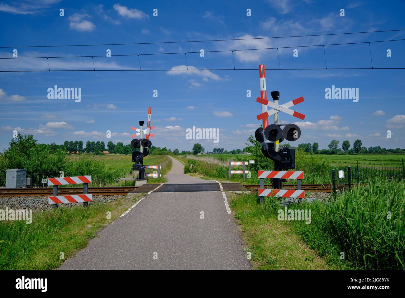 Bewachter Eisenbahnübergang mit offenen Barrieren, rotem Warnlicht und Kreuz des Heiligen Andreas in den Niederlanden. Stockfoto