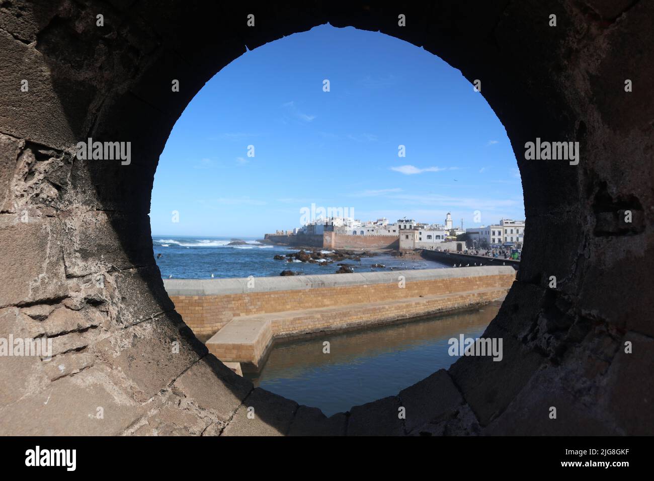Eine Nahaufnahme durch ein rundes Lochfenster zu Gebäuden am Meer Stockfoto