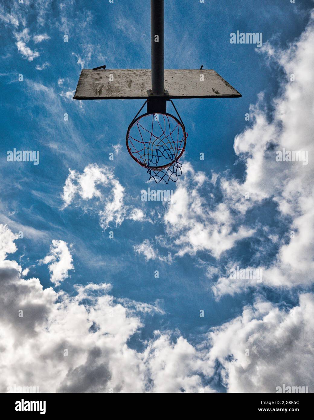 Eine Ansicht von unten auf einen Basketballkorb mit einem wunderschönen, wolkigen blauen Himmel im Hintergrund Stockfoto
