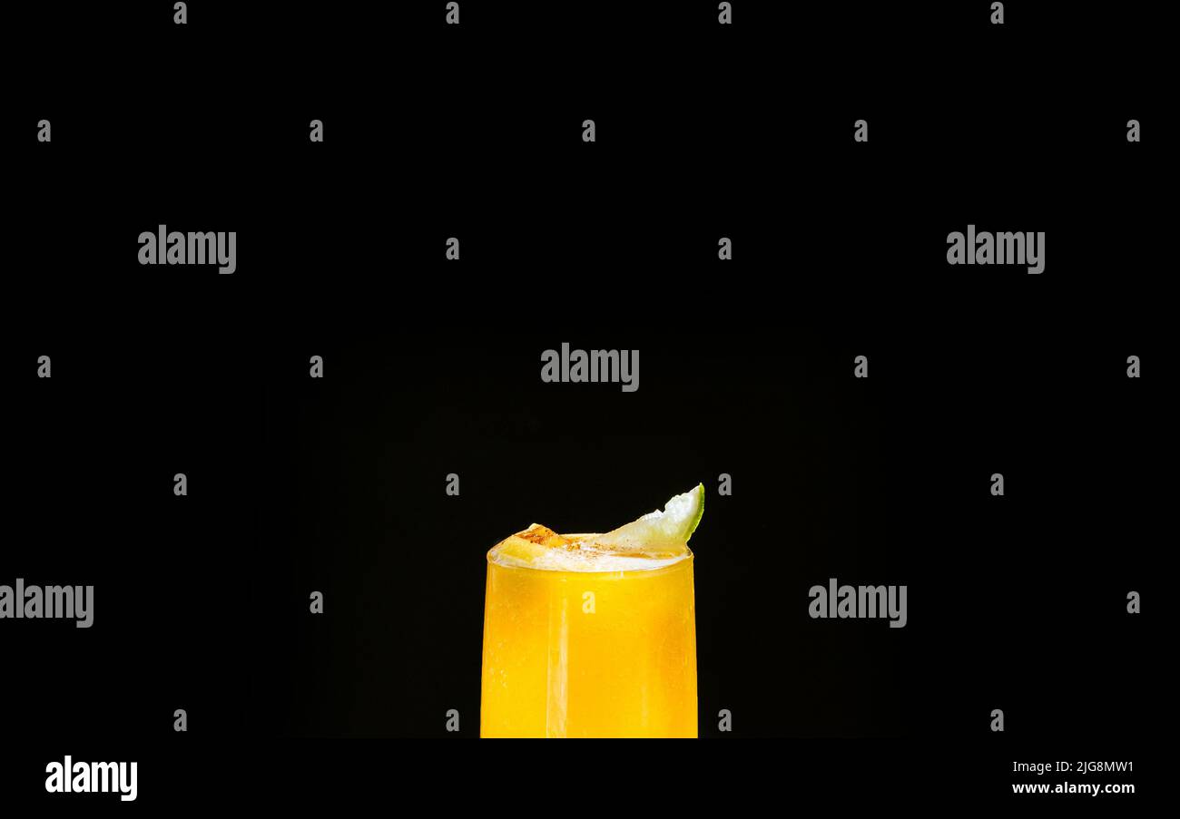 Ein mexikanisches Smoothie-Getränk aus Mango, Chilischoten, Salz und Limette. Ein erfrischender Sommer-Smoothie auf einem schwarzen Hintergrund aus leuchtendem Orange. Stockfoto