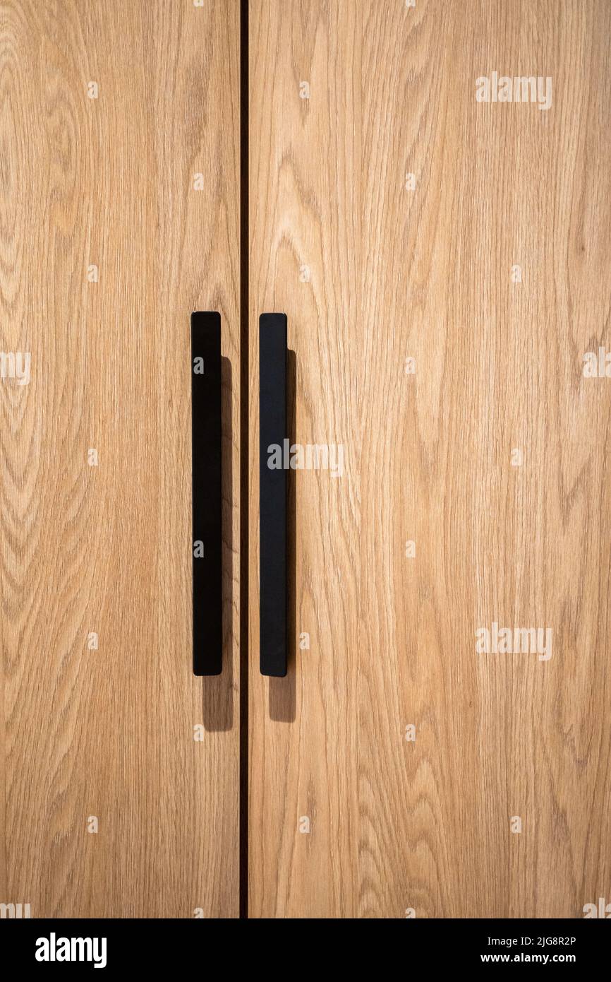 Die hölzernen Schranktüren mit schwarzen Griffen Stockfoto