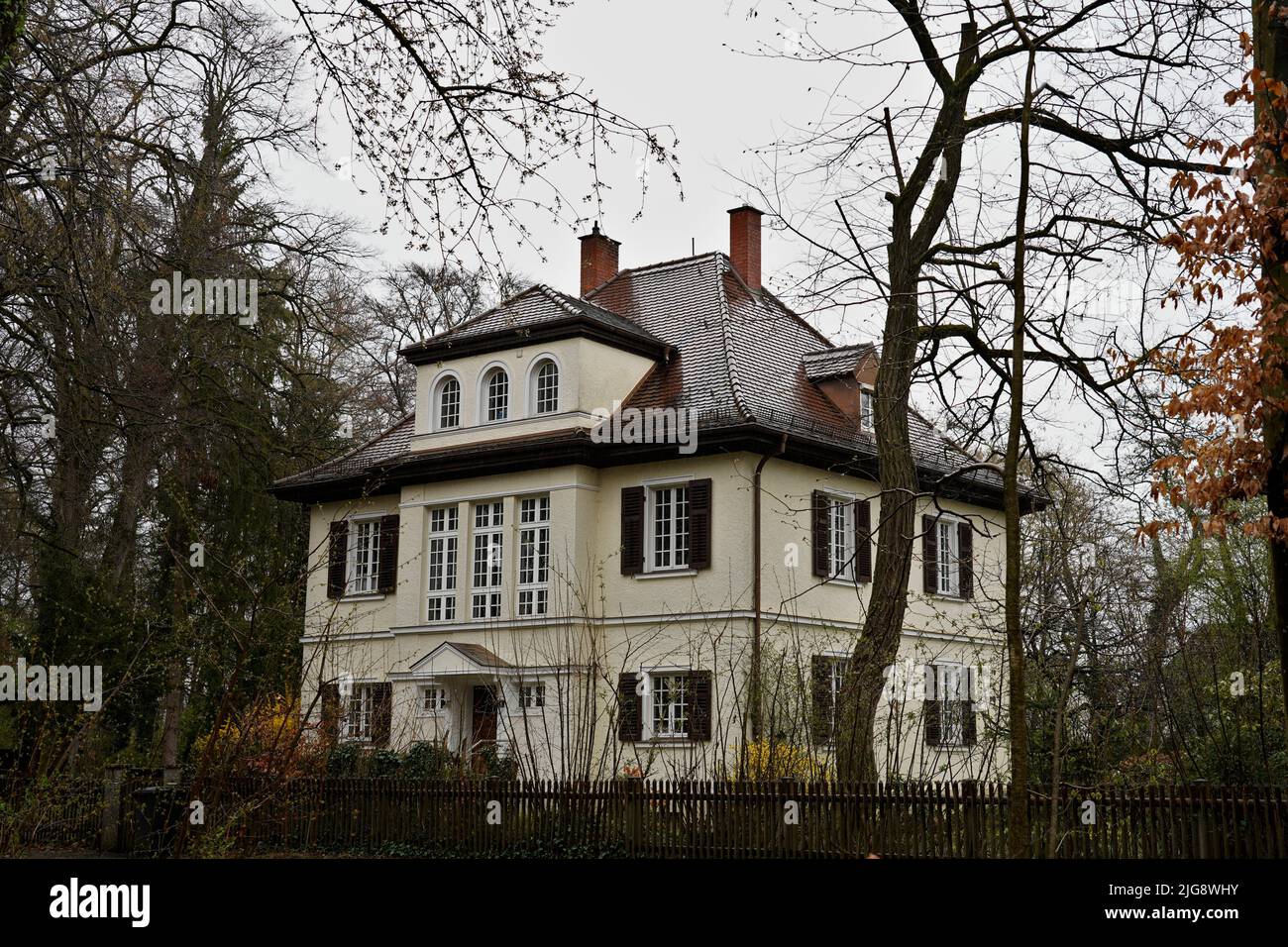 Deutschland, Bayern, Oberbayern, Altbau-Villa, Altbau-Villa, Walzdach, Fensterläden, Dachgauben, einzeln, hinter hohen Bäumen, Stadtwald, bedecktem Himmel Stockfoto