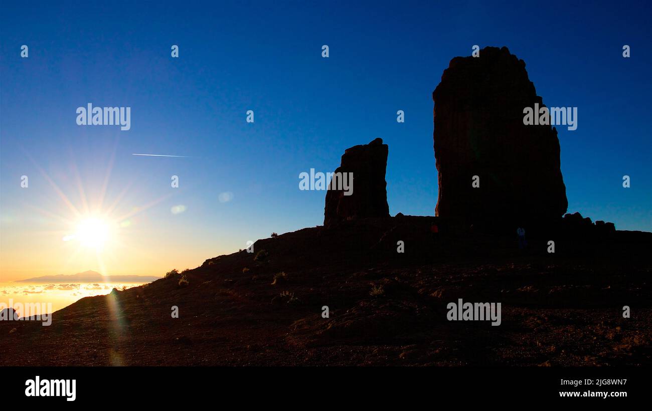 Spanien, Kanarische Inseln, Gran Canaria, Massif Central, Roque Nublo, Sonnenuntergang, Silhouette, Sonne als Stern links, zwei monolithische Felsen rechts, dunkelblauer Himmel Stockfoto