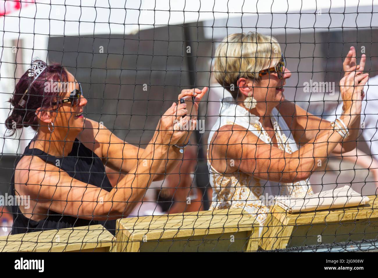 Sandbanks, Poole, Dorset, Großbritannien . 8.. Juli 2022. Die Sandpolo British Beach Polo Championships beginnen an einem heißen, sonnigen Tag am Strand von Sandbanks in Poole. Anlässlich des 15.-jährigen Bestehens die zweitägige Veranstaltung, die als größte Strandpoloveranstaltung der Welt stattfindet, findet am Freitag und Samstag statt, während Besucher sich am Strand die Action ansehen. Zwei Zuschauerinnen, die das Geschehen auf ihren Smartphones festhalten. Quelle: Carolyn Jenkins/Alamy Live News Stockfoto