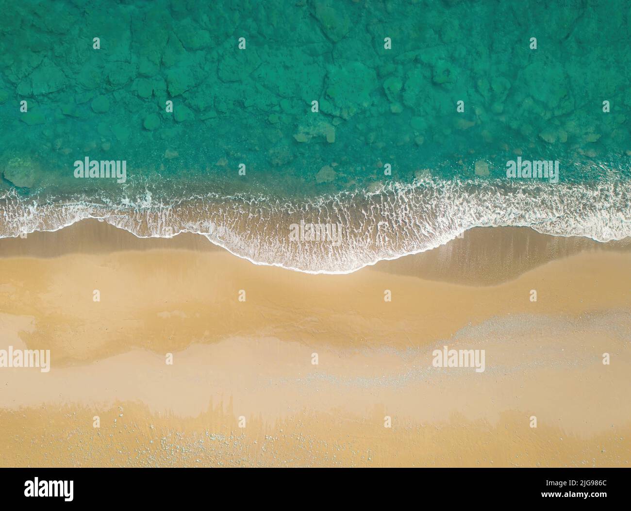Grüne Meereswellen brechen an einem goldenen Sandstrand. Draufsicht direkt oben, natürlicher Hintergrund Stockfoto