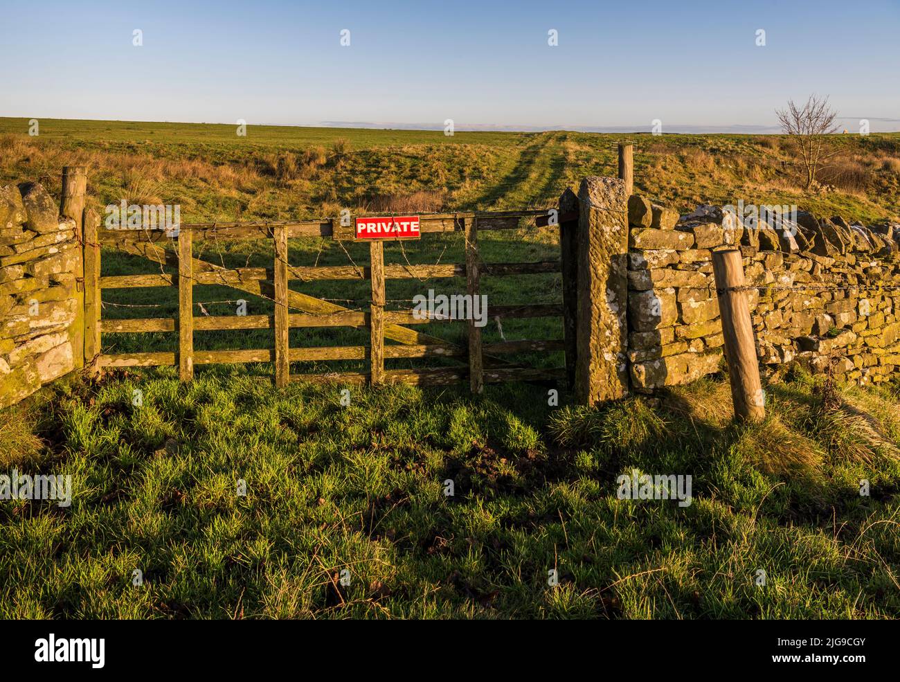 Tor mit „Private“-Schild und Stacheldraht, der den Zugang von einem öffentlichen Brückenweg nach Norden zu einem Pfad über offenes Farmland in Northumberland, England, verhindert Stockfoto