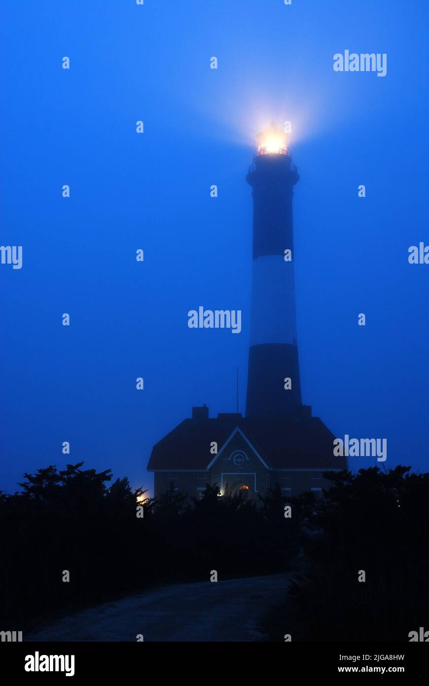 Das Leuchtfeuer des Fire Island Lighthouse leuchtet durch den nebligen und stürmischen Himmel am Strand und an der Küste Stockfoto
