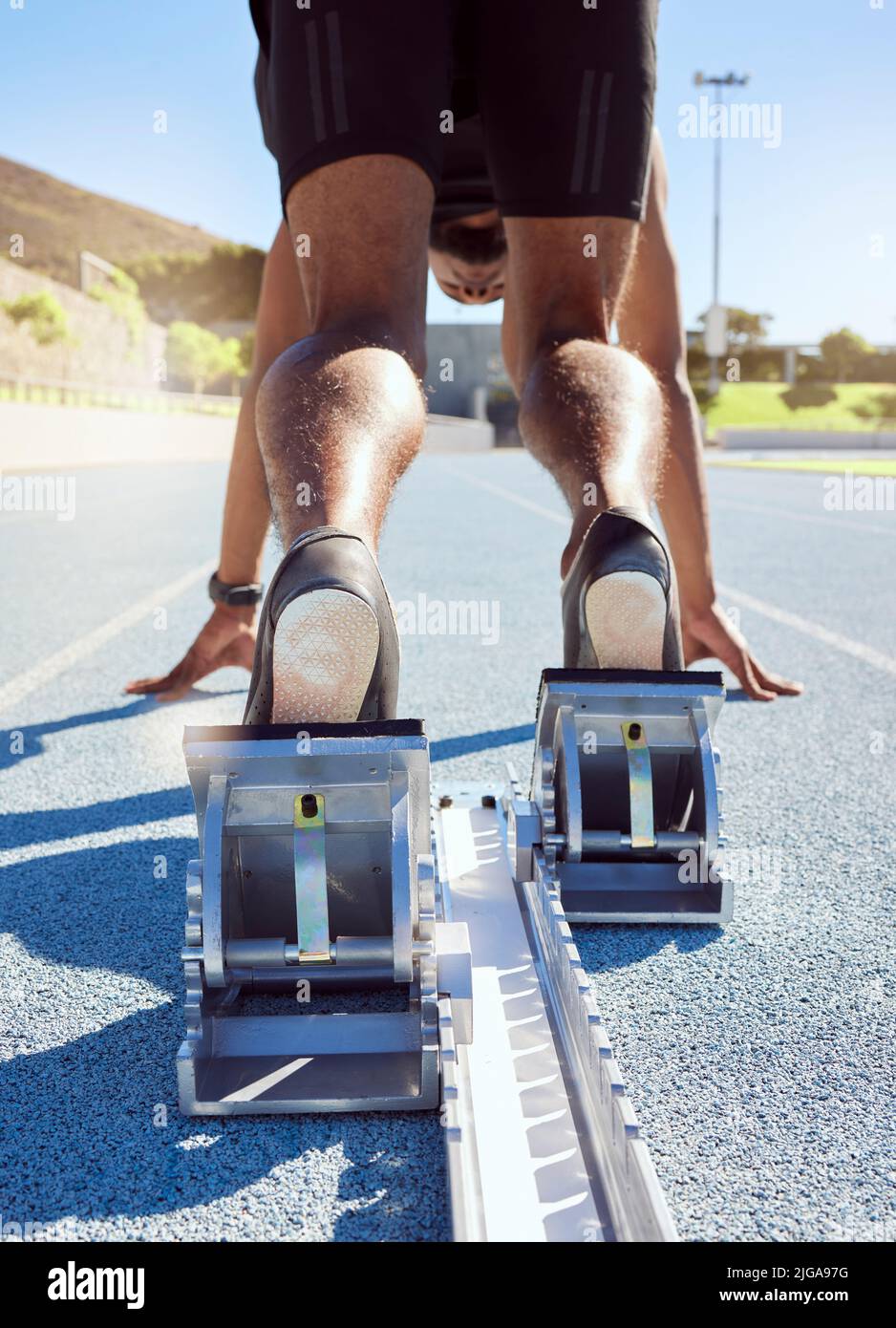 Füße des Athleten in Startposition auf einer Laufstrecke. Ein männlicher Track- und Feldläufer, der bereit ist, den Startblock zu verlassen, um seinen Sprint zu starten Stockfoto