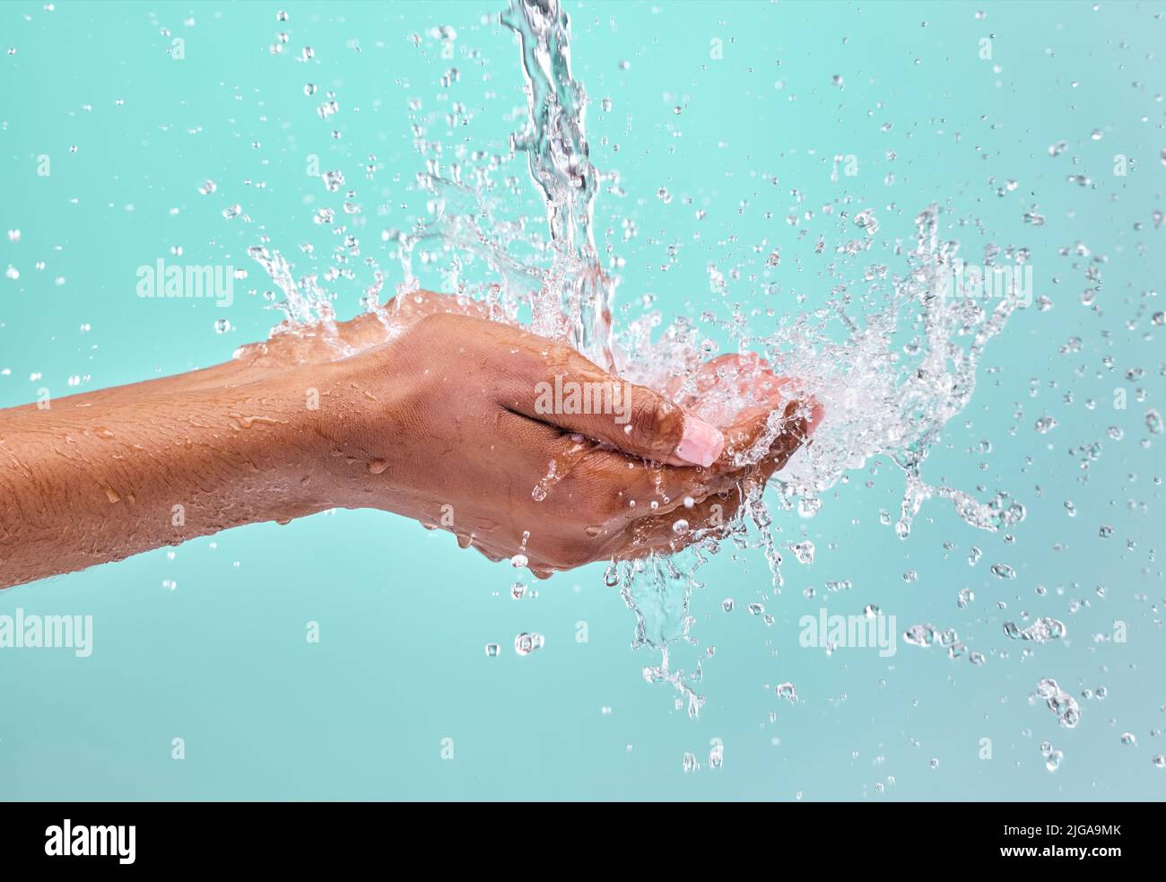 Tun Sie es für ein gesünderes Sie. Eine unkenntliche Frau schröpfen ihre Hände, um Wasser vor einem blauen Hintergrund im Studio zu fangen. Stockfoto