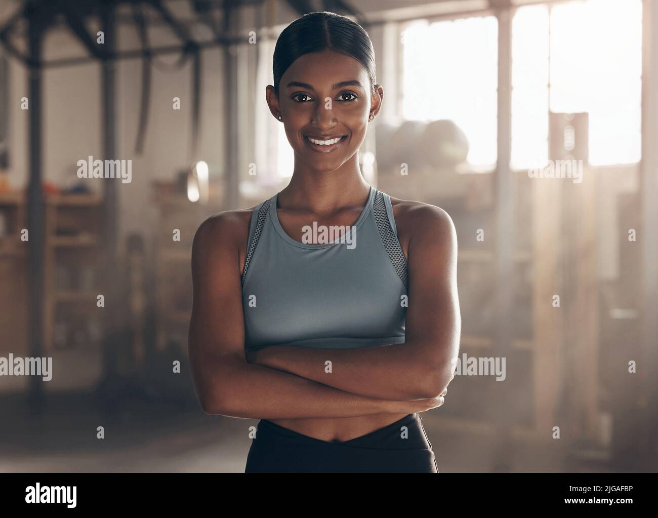 Seien Sie bereit, sich jeden Tag selbst herauszufordern. Porträt einer sportlichen jungen Frau, die mit gekreuzten Armen in einer Turnhalle steht. Stockfoto