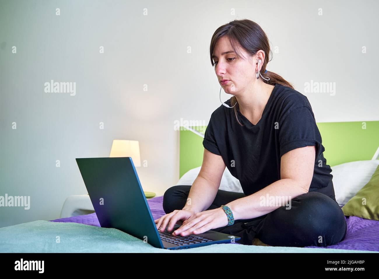 Eine kaukasische Frau, die vom Schlafzimmer aus auf den Computer schaut Stockfoto