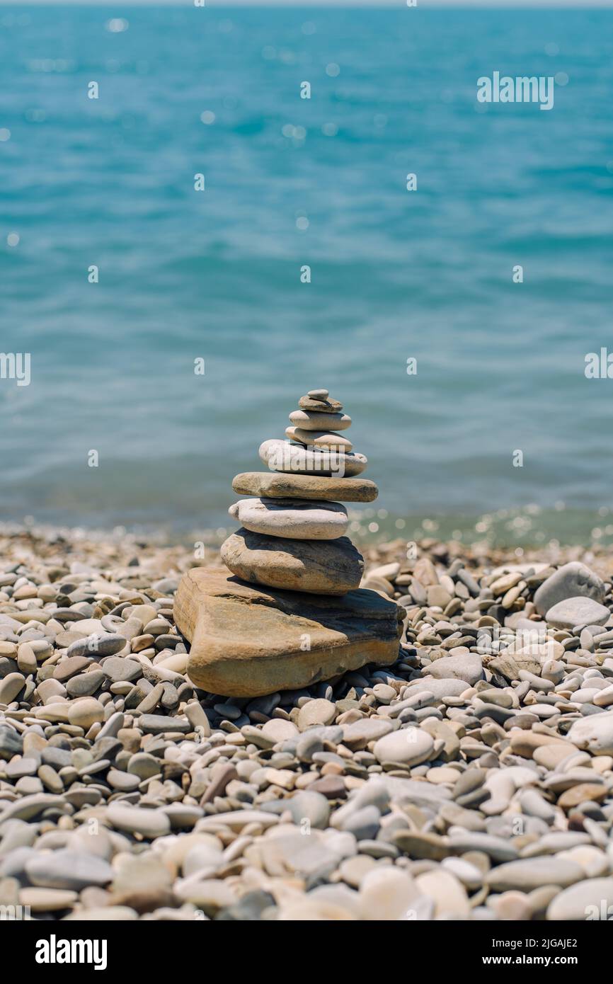 Ausgewogene Steine an einem Kieselstrand. Am Strand in einer Balancepyramide angeordnete Seesteine. Stockfoto
