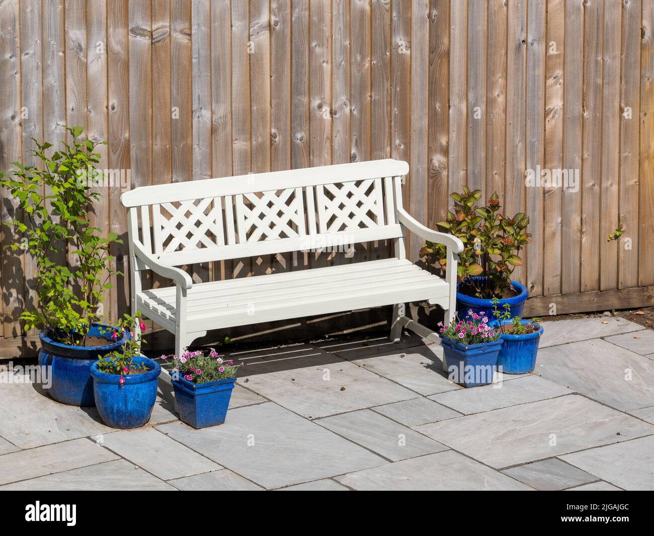 White Painted Garden Sitzbank mit bunten Topfpflanzen Blumen Stockfoto