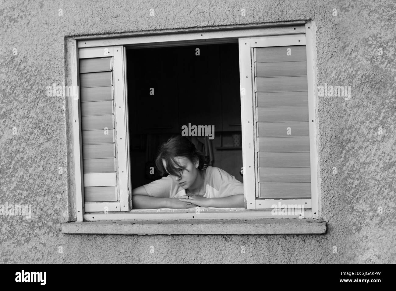 Trauriges kaukasisches Mädchen im Teenageralter in einem Fenster Stockfoto