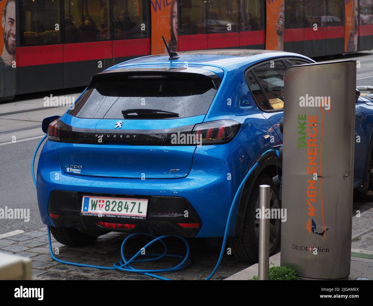 Nahaufnahme eines blauen Fahrzeugs, das an einer öffentlichen E-Car-Ladestation in Wien geladen wird Stockfoto