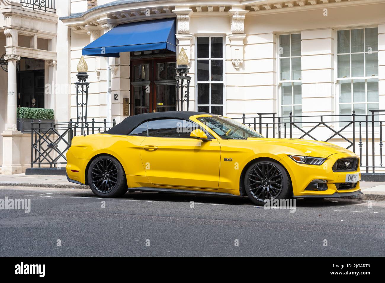 Gelbes Ford Mustang Muscle Car, das vor dem Grundstück in der Charles Street, Mayfair, London, Großbritannien, geparkt wurde. Exklusive Wohnimmobilien im teuren Mayfair Stockfoto