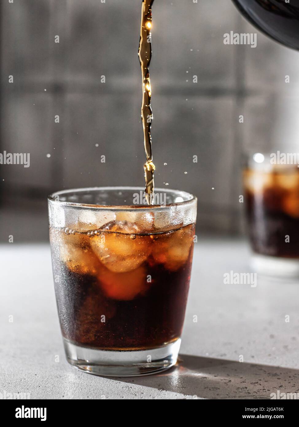 Cola oder cuba Libre Cocktail in Glas mit Eiswürfeln gießen. Softdrink mit Spritzwasser. Vertikale Ausrichtung Stockfoto