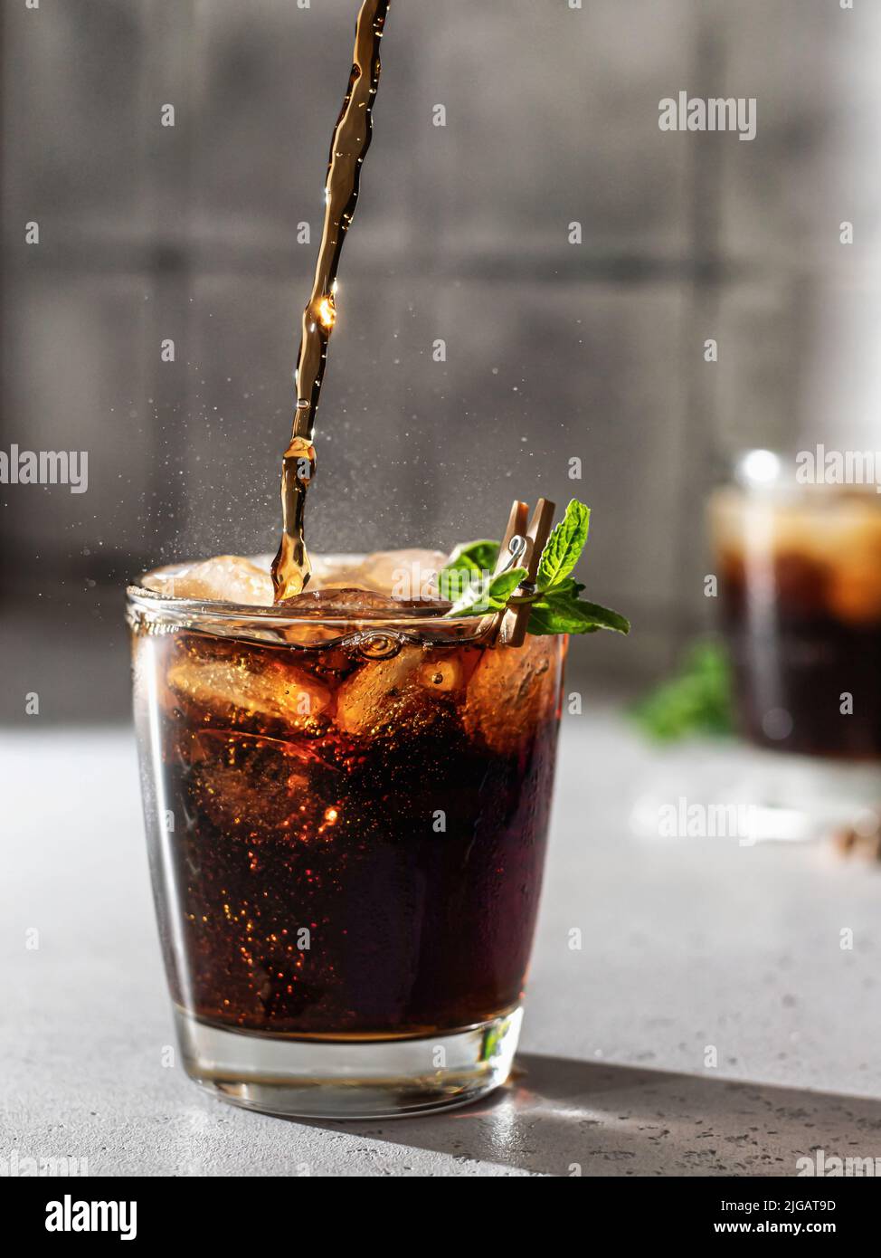 Cola oder cuba Libre Cocktail in Glas mit Eiswürfeln und Minze gießen. Softdrink mit Spritzwasser. Vertikale Ausrichtung Stockfoto