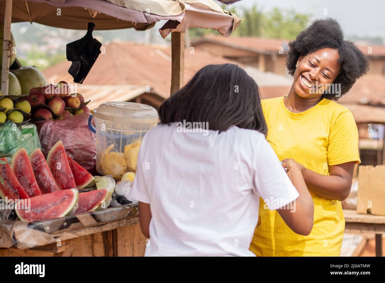 afrikanische Dame, die Früchte von einer Marktfrau kauft Stockfoto