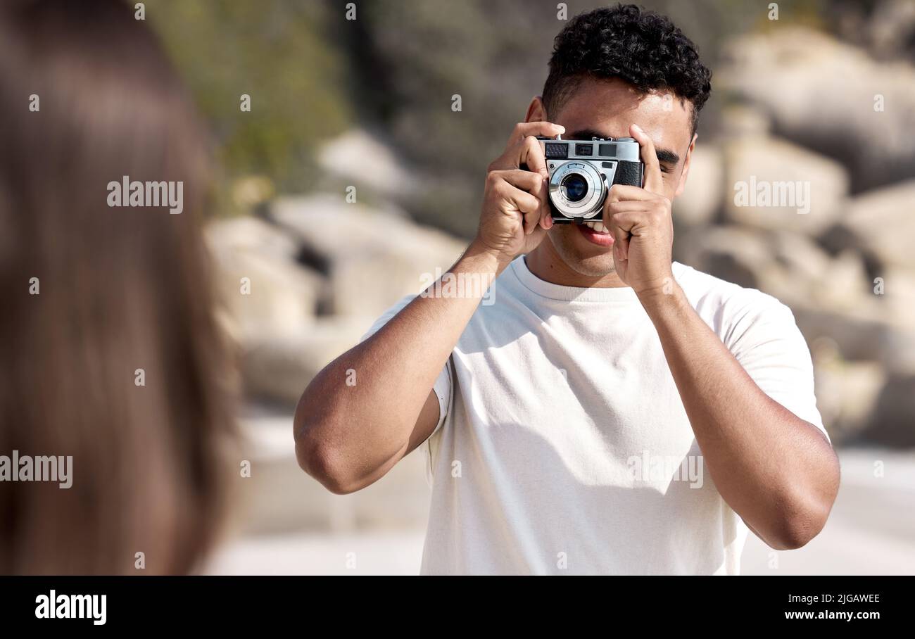 Pose für das Bild. Ein junger Mann fotografiert seine Freundin am Strand. Stockfoto