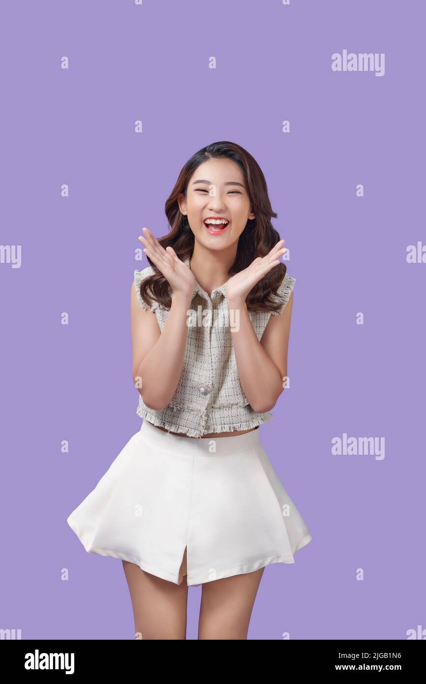 Porträt einer sehr glücklichen, jovial lachenden schönen jungen asiatischen Frau vor purpurem Hintergrund isoliert Stockfoto