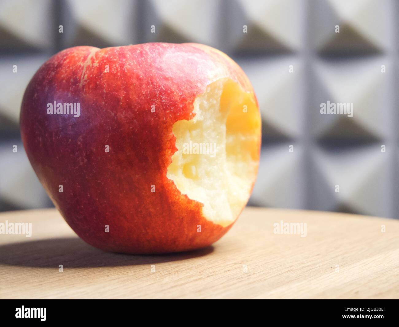 Ein gebissene Apfel auf einer Holzoberfläche. Makro „Reifer Apfel“. Stockfoto