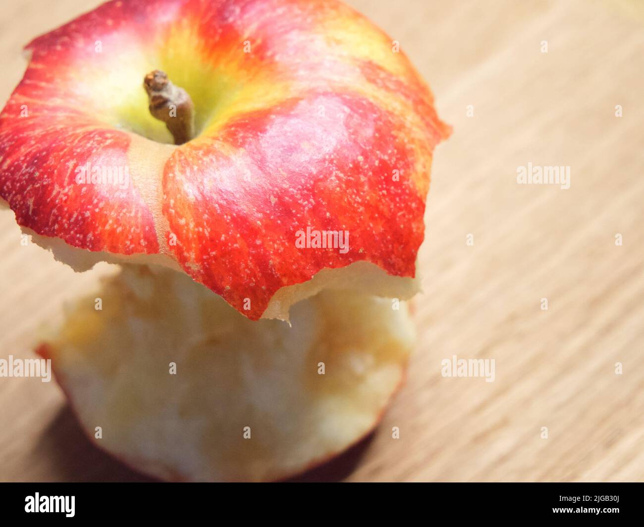 Roter Apfelkern auf einem Holzhintergrund. Ein gebissene Apfel aus der Nähe. Stockfoto