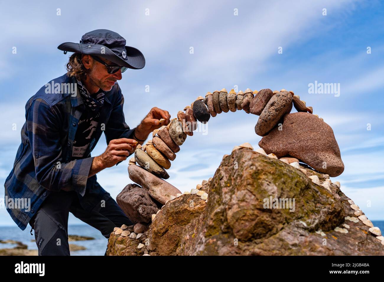 Dunbar, Schottland, Großbritannien. 9. Juli 2022. Tag eins der Stone Stacking Championships 11. am Eye Cave Beach in Dunbar in East Lothian. . Die Konkurrenz wird während des Wettkampfes im Bogenbau gezeigt. PIC; Pedro Duran und sein Steinbogen. Iain Masterton/Alamy Live News Stockfoto