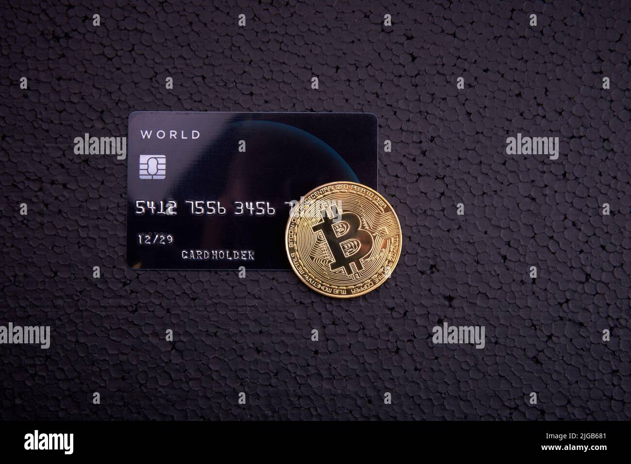 goldmünze Bitcoin und Kreditkarte auf schwarzem Hintergrund Stockfoto