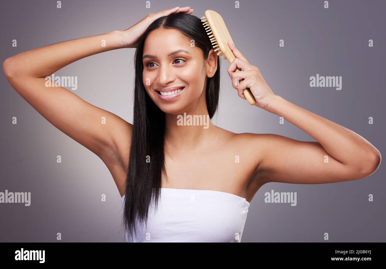 Bürste für gesundes Haar. Eine attraktive junge Frau, die allein im Studio steht und sich die Haare putzt. Stockfoto