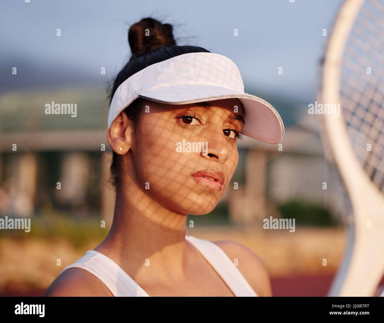 Ich Spiele Tennis. Eine sportliche junge Frau, die mit einem Tennisschläger auf einem Platz posiert. Stockfoto
