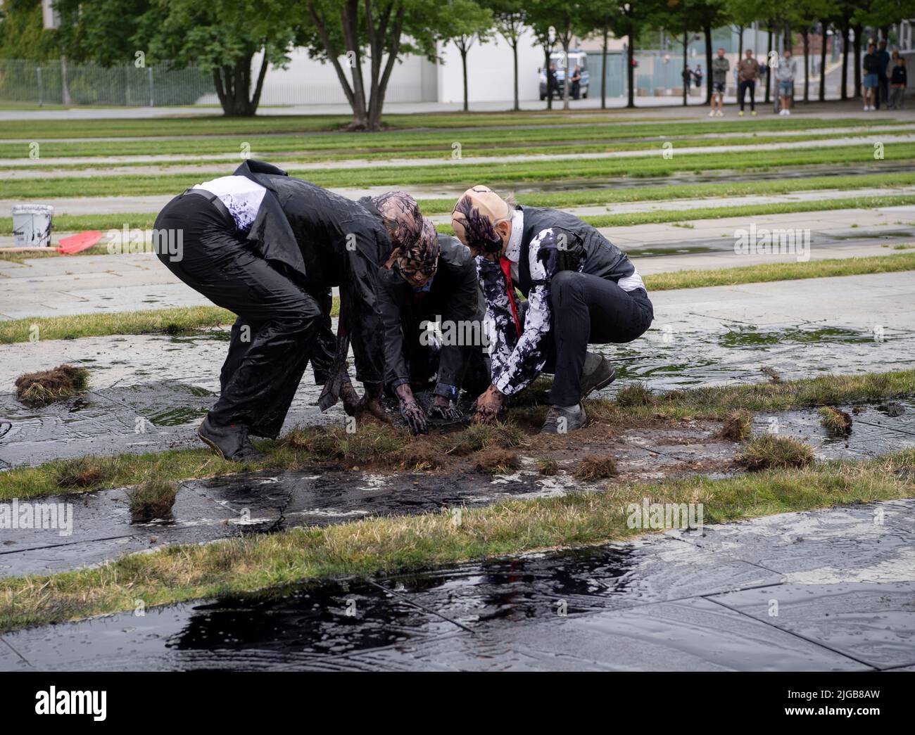 Berlin, Deutschland. 09.. Juli 2022. Klimaschutzaktivisten der Gruppe "Last Generation" graben vor dem Kanzleramt nach "Öl". Zuvor hatten sie eine ölähnliche Farbsubstanz verschüttet. Nachdem die Polizei zunächst versuchte, die Aktivisten mit Worten zu stoppen, rissen sie sich später nieder und fesselten die Aktivisten mit Handschellen. Quelle: Paul Zinken/dpa/Alamy Live News Stockfoto